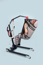 hombre suspendido en grúa para pacientes eléctrica inalámbrica, usando un arnés de rehabilitación Victoria. Vista lateral izquierda