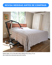 grúa para pacientes junto a una cama en la habitación de una casa, mostrando sus dimensiones.