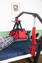 paciente con piernas elevadas por la grúa para pacientes y usando el arnés cambia pañal para pacientes en cama