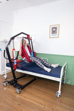 paciente usando arnés cambia pañal levantado con grúa para pacientes, vista completa 