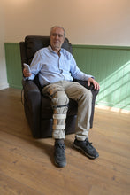 hombre sentado en sillón ortopédico, sosteniendo el control  de mando